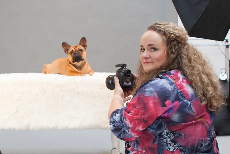 Esther Vinju achter haar camera in de studio, met een Franse bulldog op de set